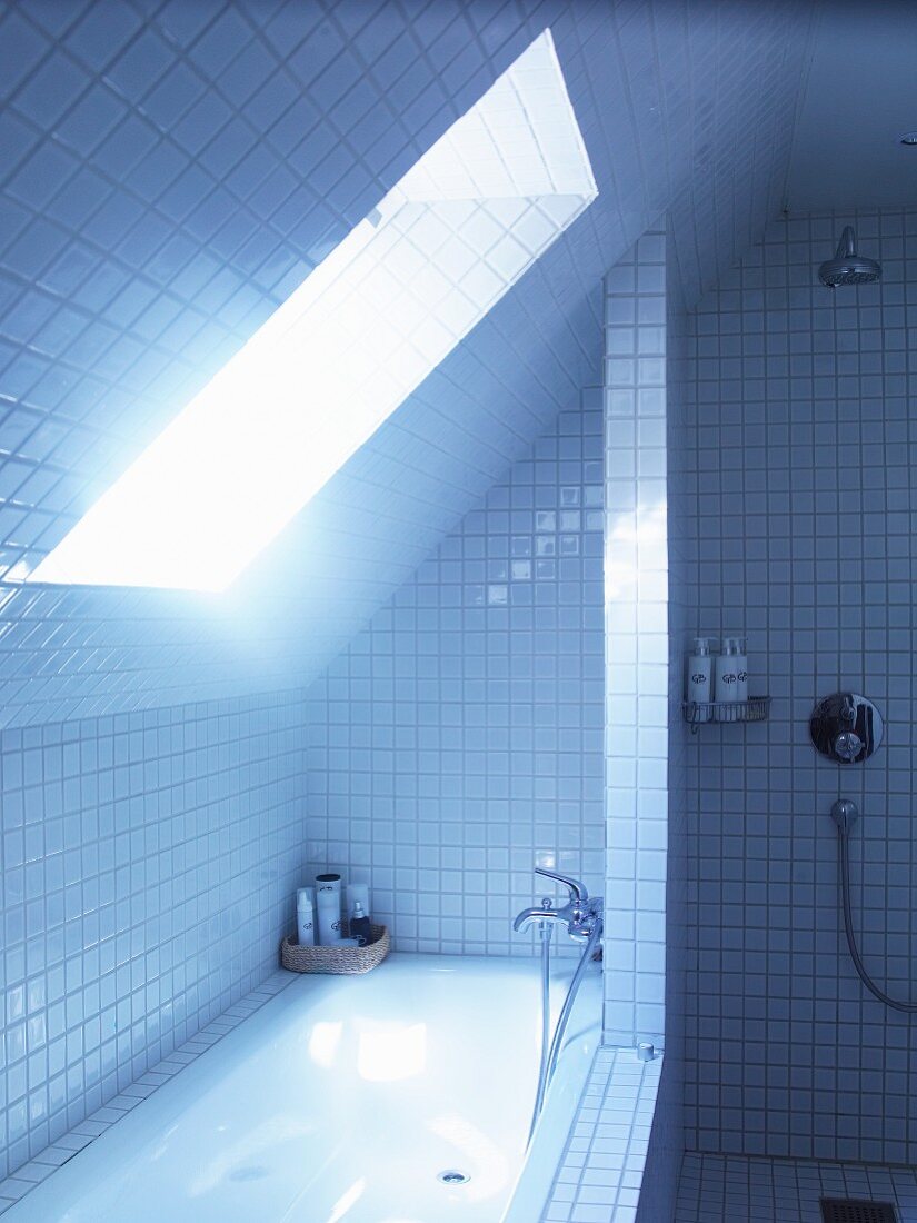 Unter Dachschräge eingebautes Bad mit weissen Fliesen an Wand, Badewanne und Boden