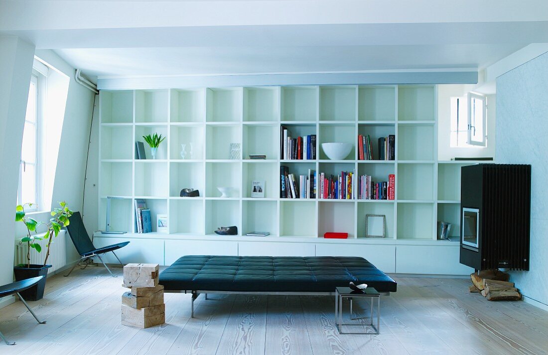Black leather couch and white fitted shelving with square compartments
