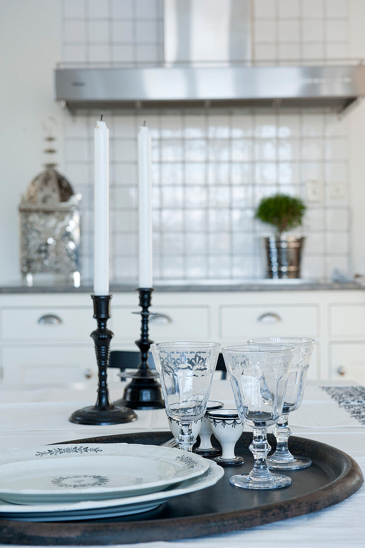 Tablett mit Teller und Kristallgläser vor Kerzenständer auf Tisch in Landhausküche