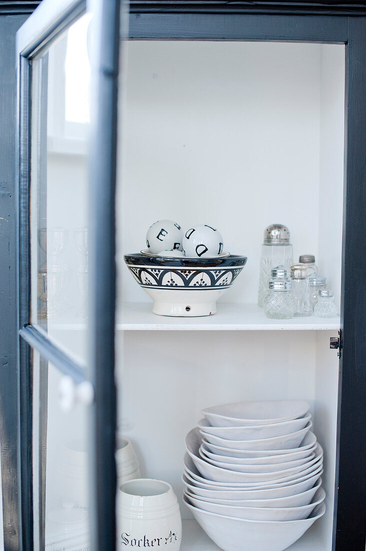 White crockery in open cupboard with glass door