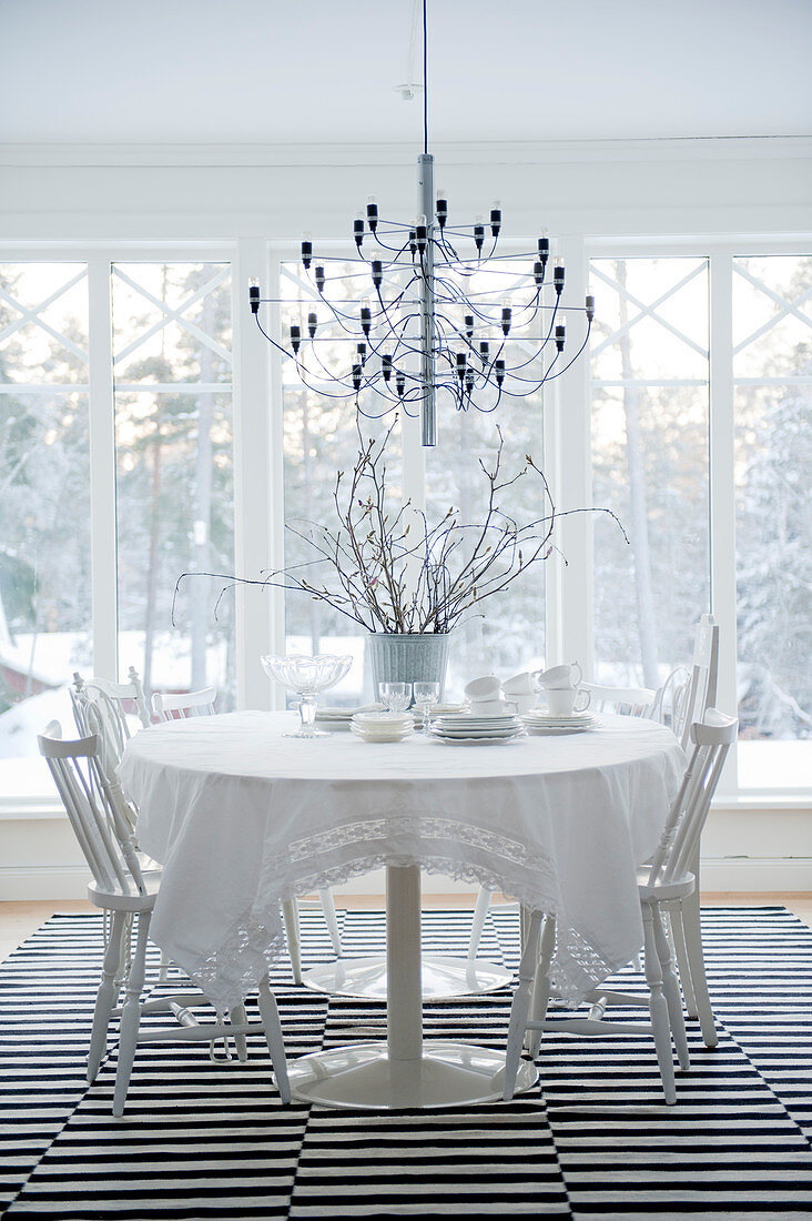 Designer Hängeleuchte über Esstisch und Stühle in Weiß auf Teppich mit schwarz-weissen Streifen
