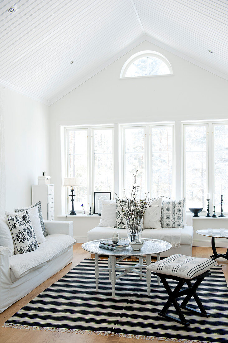 Heller Wohnraum im Dachgeschoss mit weisser Polstergarnitur und orientalischem Beistelltisch auf schwarz-weißem Teppich