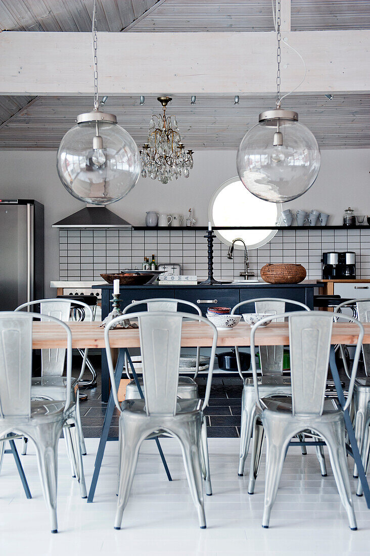 Industrial lamps and crystal chandelier above dining table in open-plan kitchen