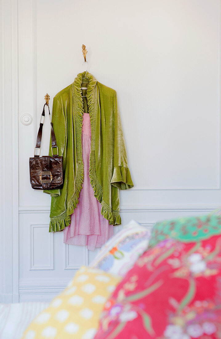 Hellgrüner Morgenmantel über Nachthemd und Tasche an Wandhaken aufgehängt im Schlafzimmer mit traditionellem Flair