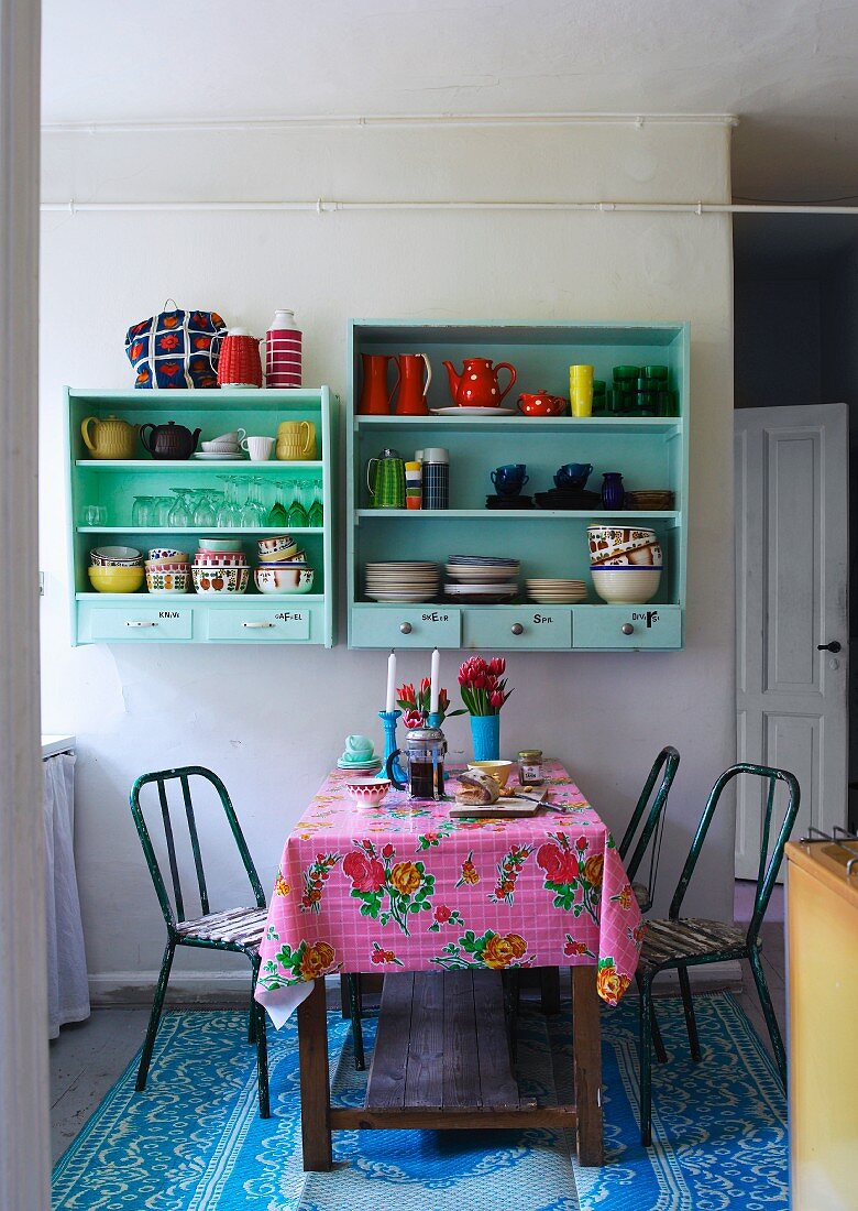 Esstisch mit buntem Wachstuch und pastellgrün lackierte Küchenboards an Wand