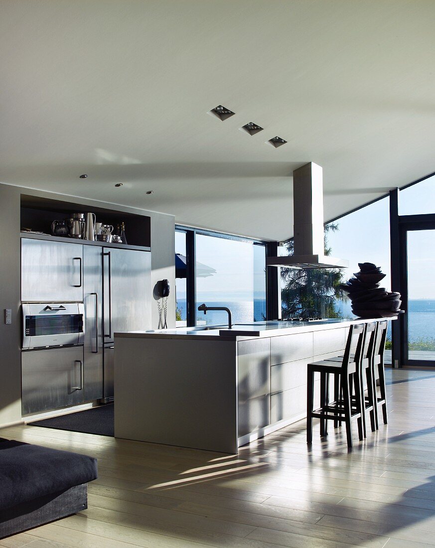 Designer kitchen with free-standing kitchen island in front of glass wall