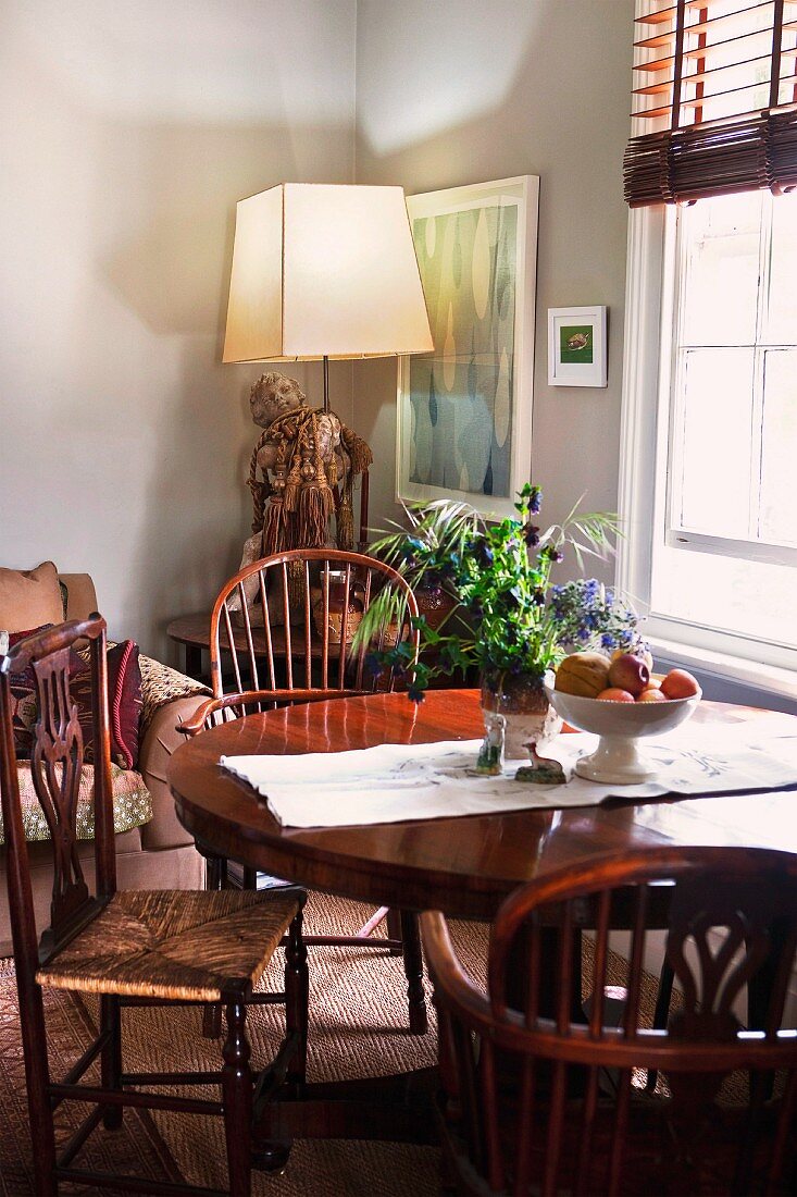 Englische Stühle und Rundtisch im Wohnzimmer vor abstraktem Gemälde und Beistelltisch mit moderner Lampe
