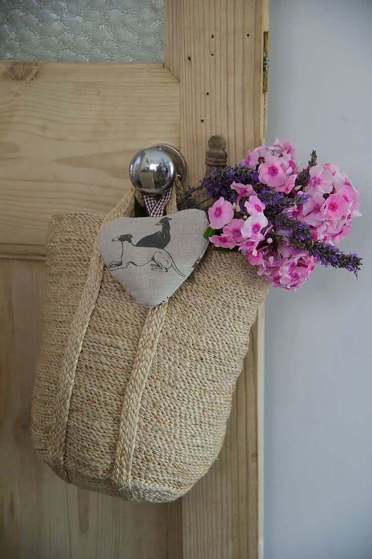Gestrickte Tasche mit Blumenstrauss und Stoffherz am Türknopf