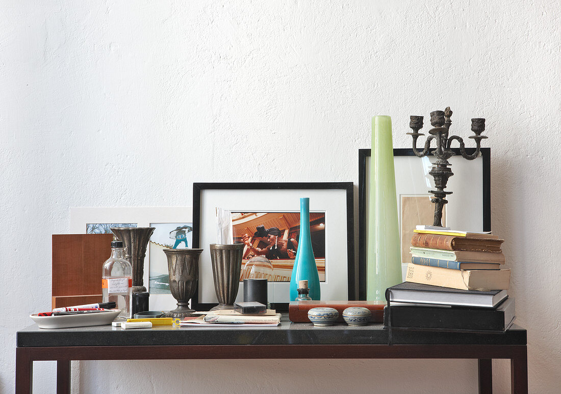 Pewter goblets, vases, stack of books and knick-knacks on modern console table