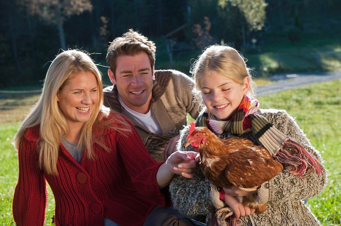 Familie mit lebendigem Huhn auf einer Wiese