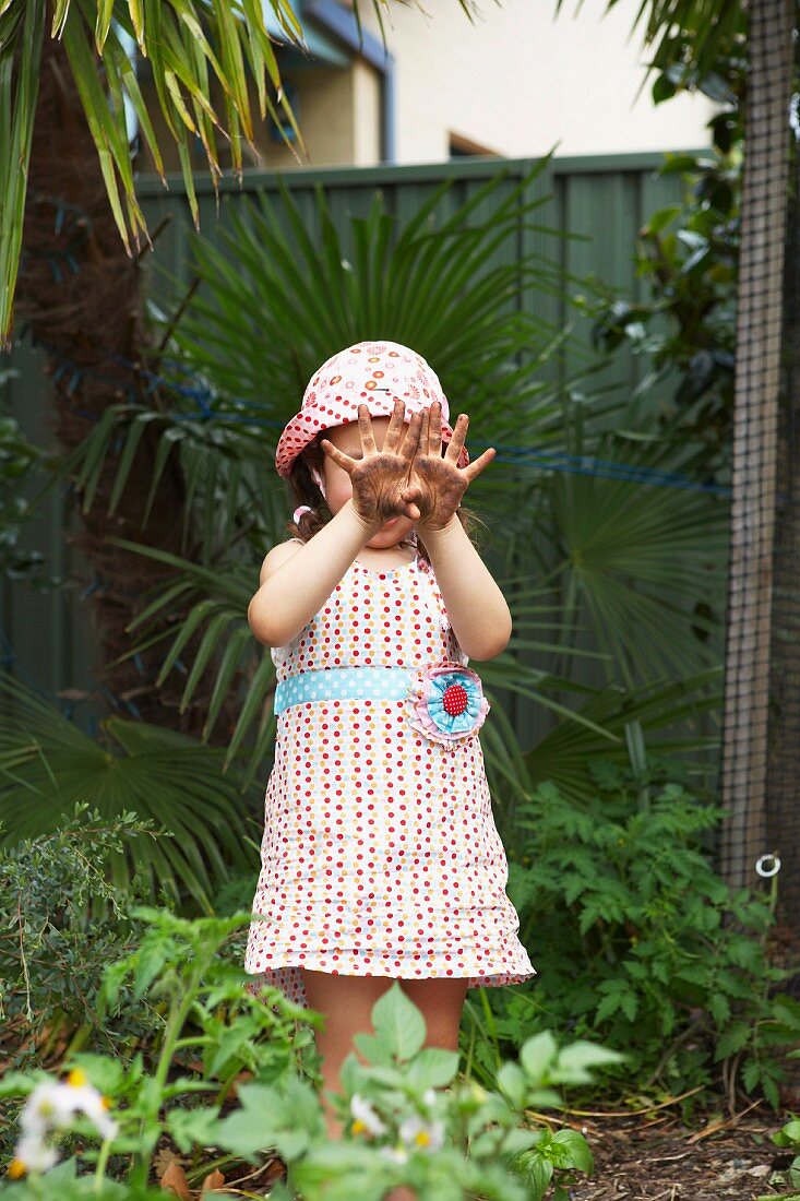 Kleines Mädchen zeigt ihre von der Gartenarbeit verschmutzten Hände