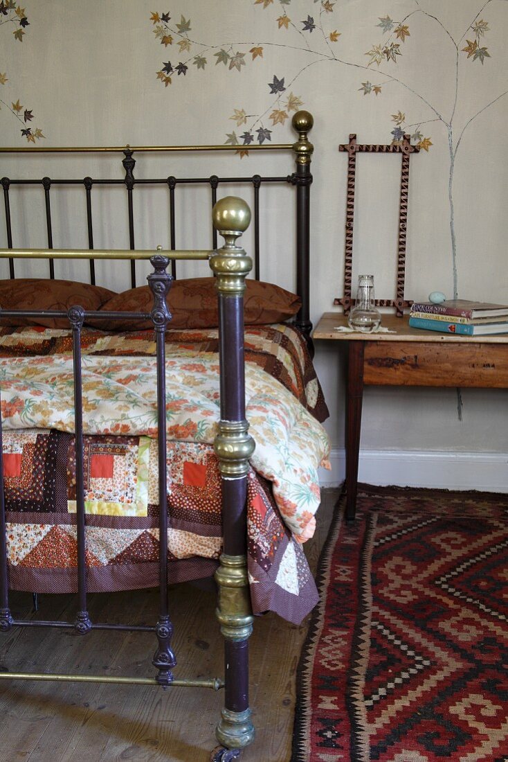 Doppelbett mit Messinggestell und gemusterter Teppichläufer in rustikalem Ambiente