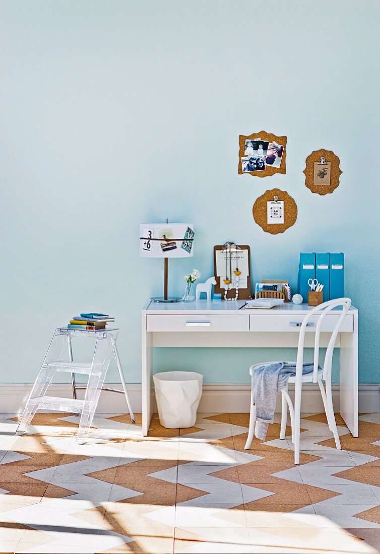Kleiner weisser Schreibtisch & transparente Trittleiter als Ablage in hellblauen Raum mit Korkboden
