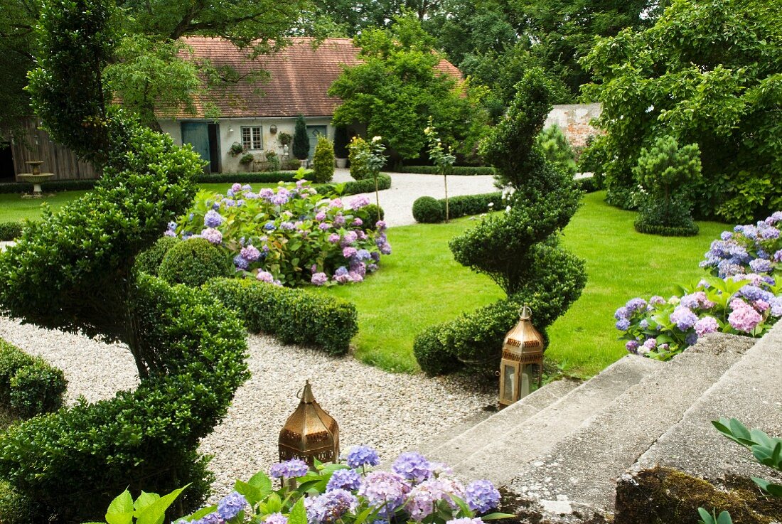 Sommergarten auf zwei Ebenen mit blühenden Hortensien und Buchs-Spiralen