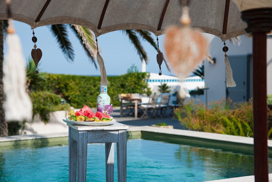 Sunny day beside the pool with refreshing fruit platter on stool