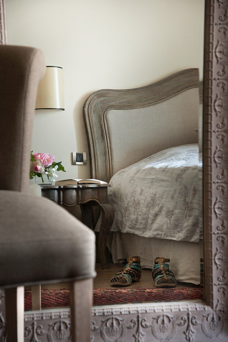Mit Ornamenten gerahmter großer Spiegel an Wand im femininen eleganten Schlafzimmer