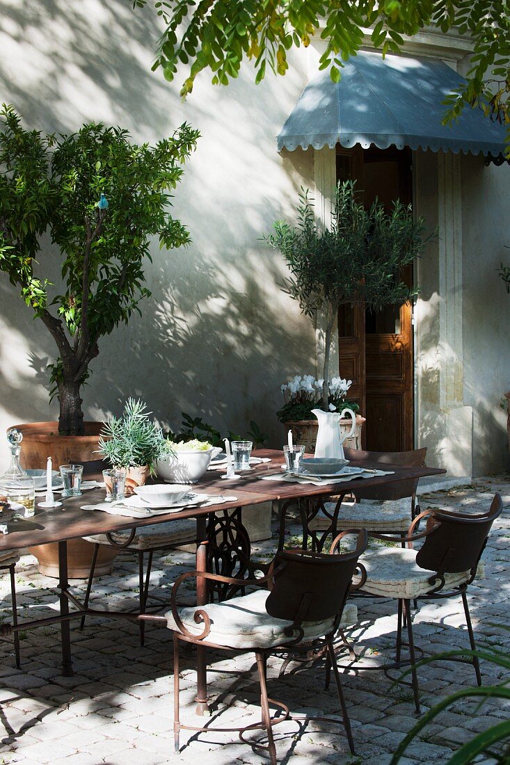 Terrassenplatz mit langem Tisch und Stühlen vor dem Haus unter Akazienbaum