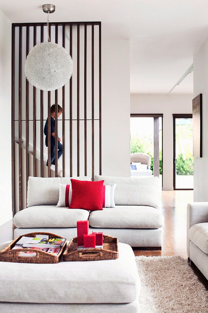 Kind steigt Treppe hinunter zum modern eingerichteten Wohnzimmer mit weisser Couchgarnitur