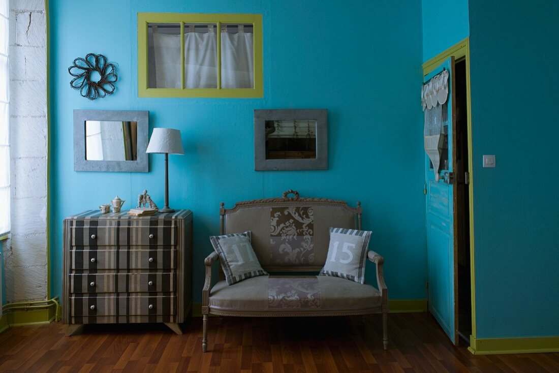 Selbstgestaltete Farb- und Stoffharmonien in einem Schlafzimmer - grau gestreifte Kommode passend zu Antiksofa vor blau und grün getönter Wand