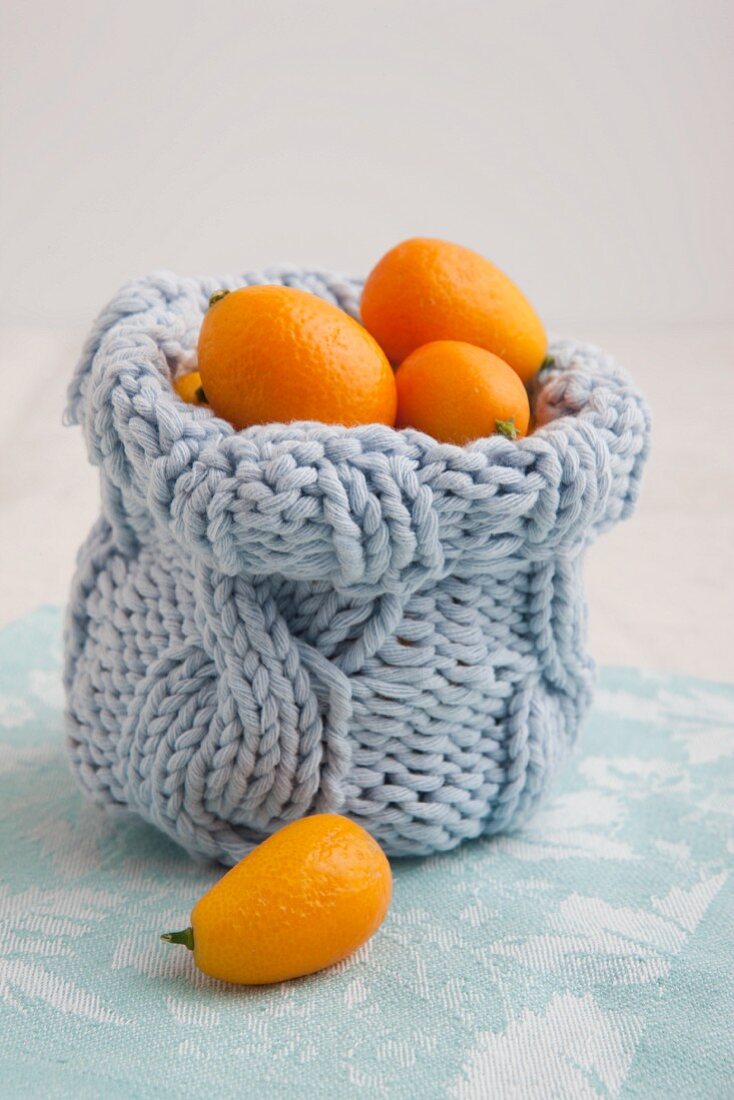 Gestricktes Gefäß mit Kumquats gefüllt