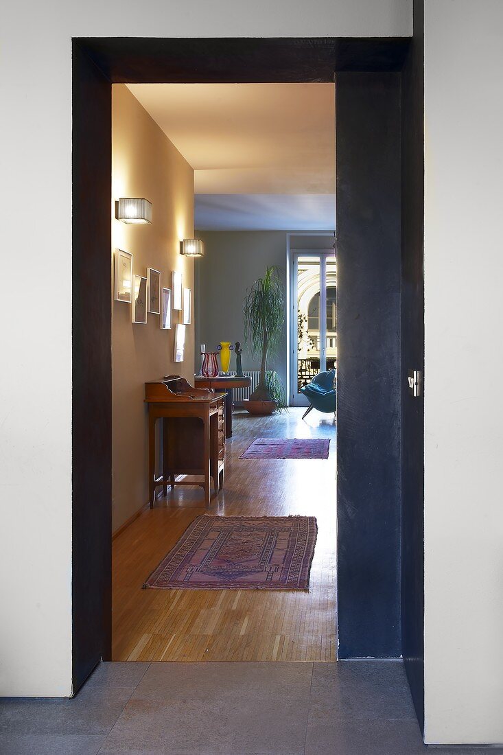 Blick durch offene Schiebetür in modernem Wohnraum mit traditionellem Flair - Teppichläufer auf Parkettboden und antiker Sekretär
