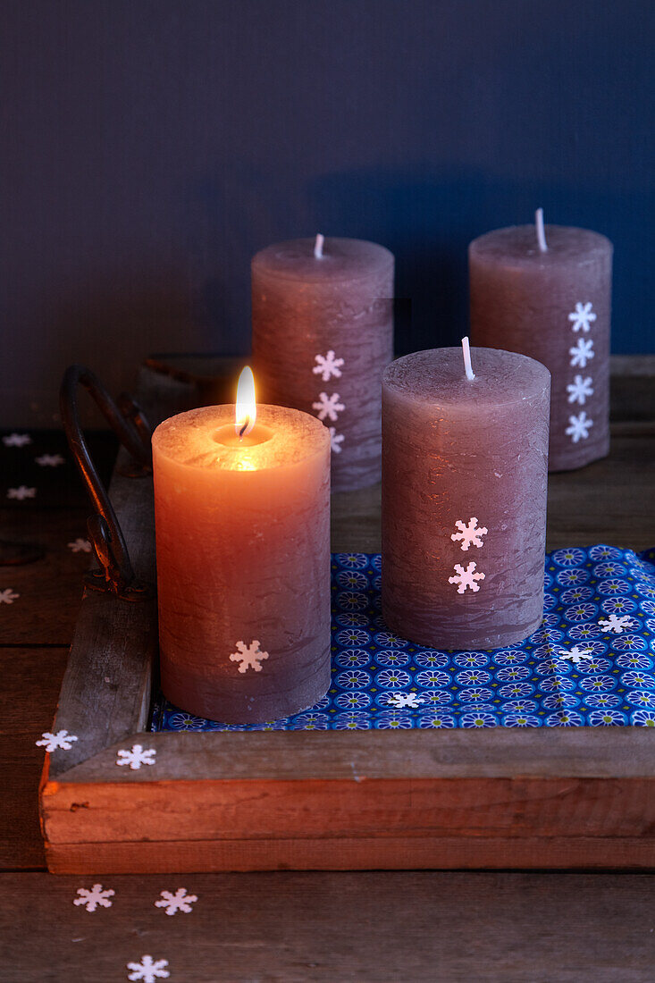 Group of candles on rustic wooden tray with Christmas decorations