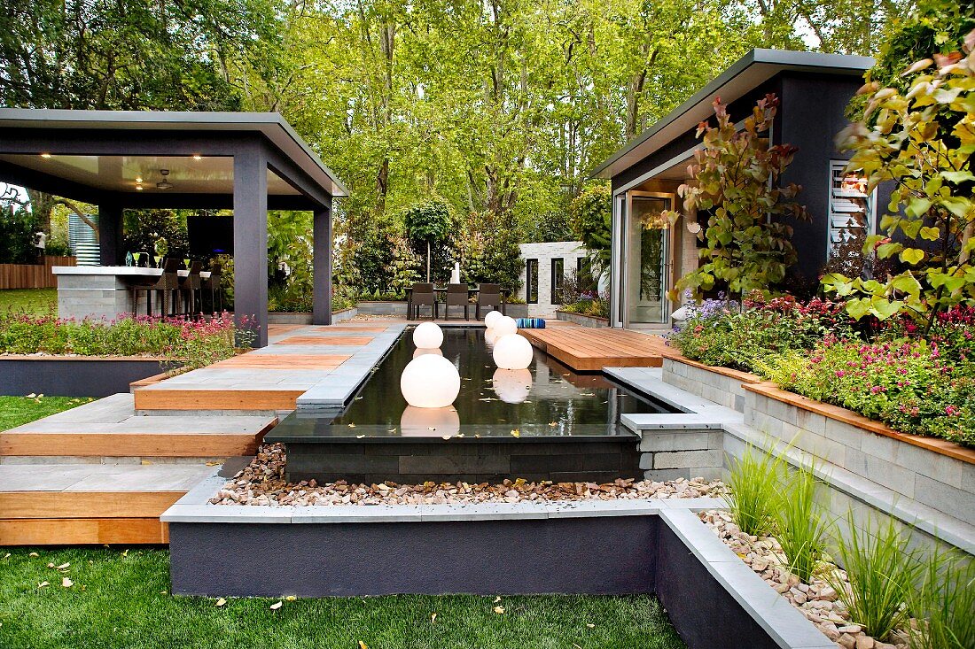 Japanisch anmutende Gartengestaltung - erhöhte Terrassenanlage mit schwimmenden Leuchtkugeln in einem schwarzem Wasserbecken