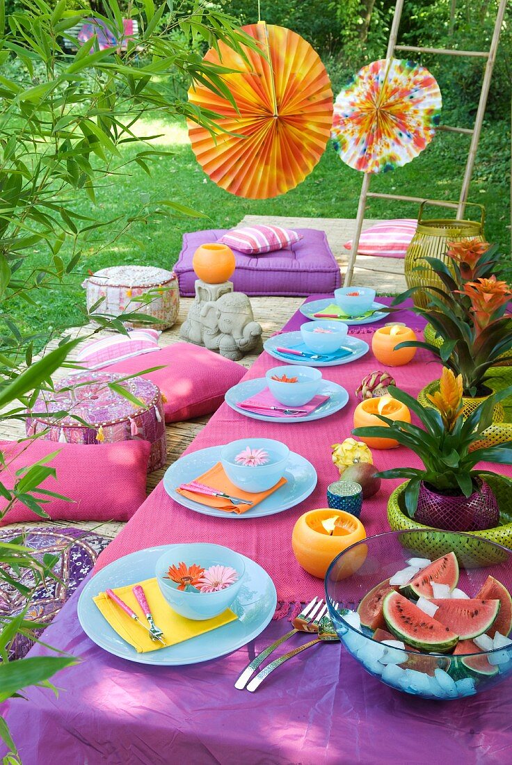 Orientalisches Gelage im Garten mit pastellblauem Geschirr zu Tischdecken und Sitzkissen in Violetttönen