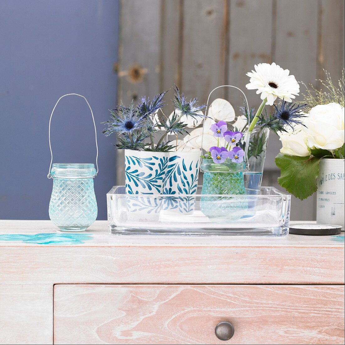 weiße und blaue Blumen in Vasen auf Kommode