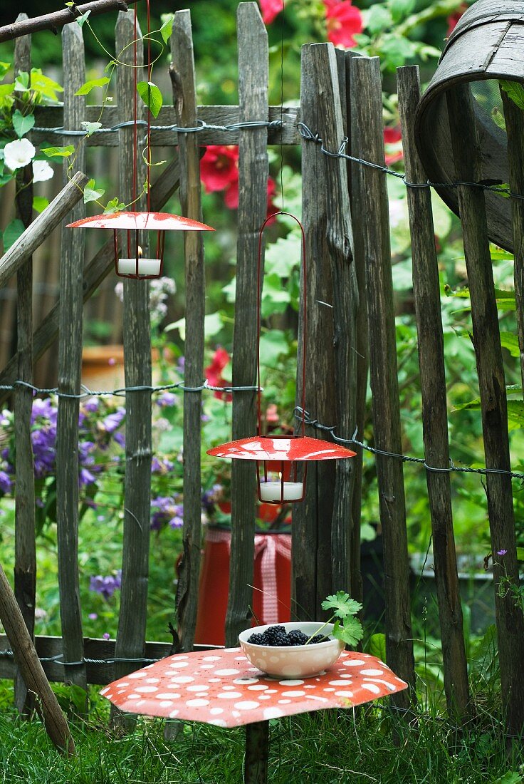 Windlichter mit roten Metallhauben als Deko im Bauerngarten