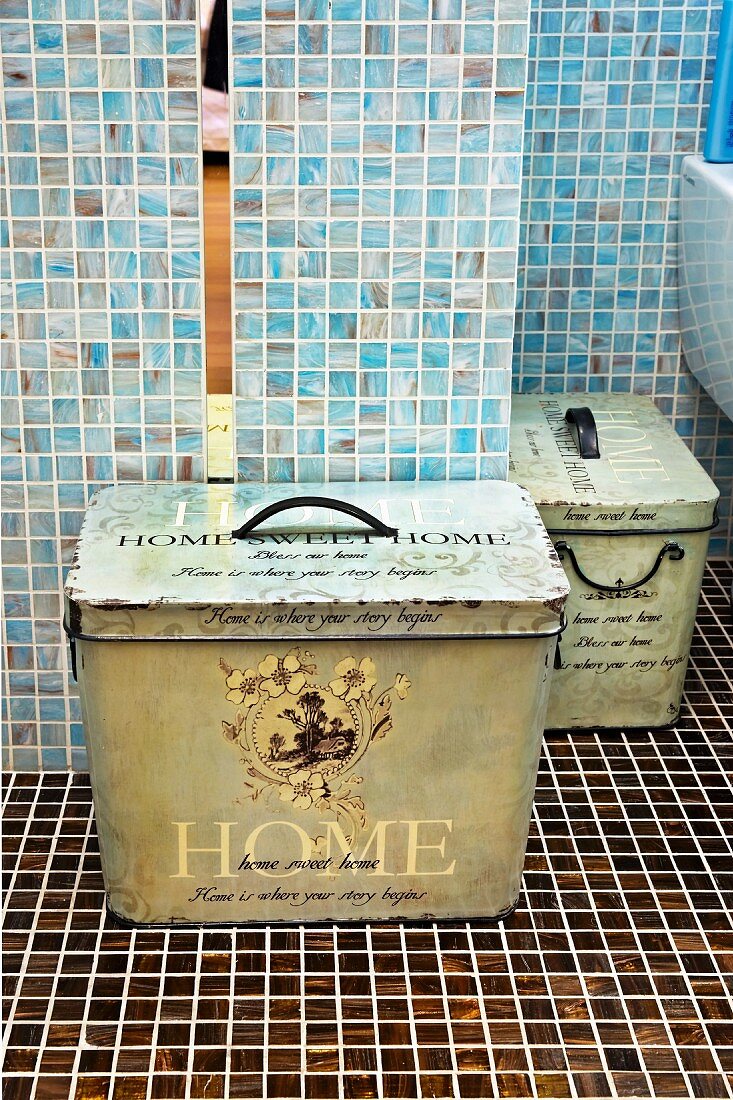 Vintage Metall Aufbewahrungsboxen im Bad vor hellblauen Wandflliesen auf dunkelbraunen Mosaikbodenfliesen