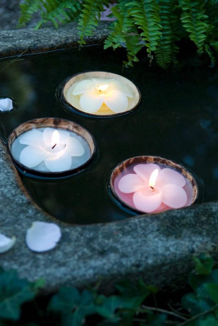 Blütenförmige Kerzen in schwimmenden Kokosschalen