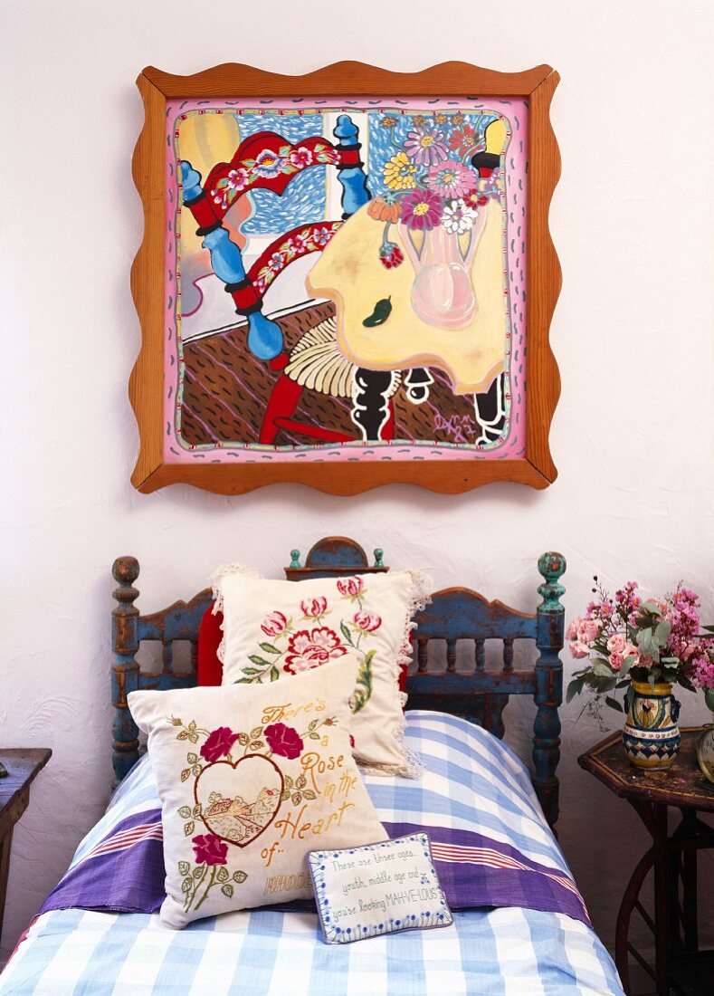 Modernes Pop Art Gemälde über einem rustikalen Bauernbett mit floralen Kissen und karierter Tagesdecke