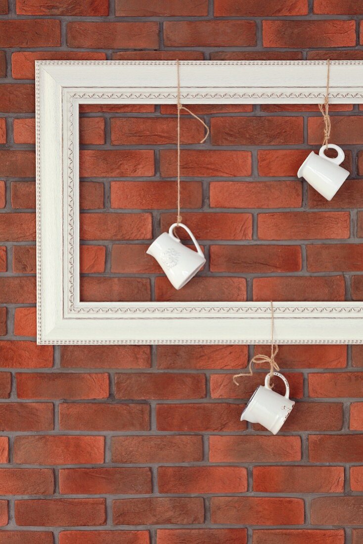 Milk jugs hanging from empty picture frame against brick wall