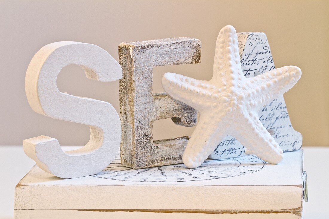 White-painted wooden letters and starfish figurine on wooden box