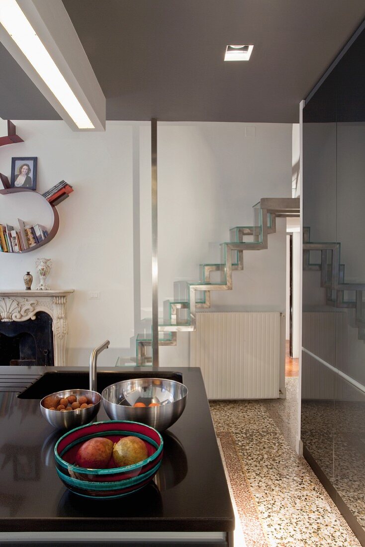 Various dishes on kitchen island in front of modern samba staircase with stainless steel frame