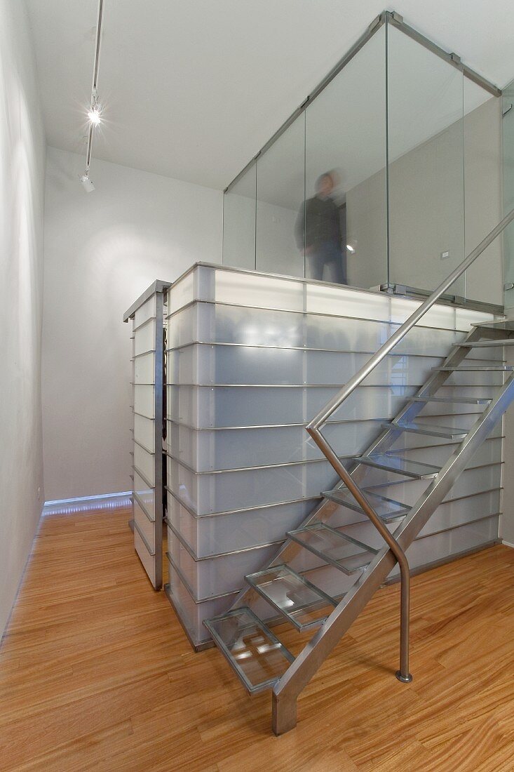 Treppe aus Edelstahl neben Einbau aus Glas-Stahlkonstruktion, darüber verglaster Bereich
