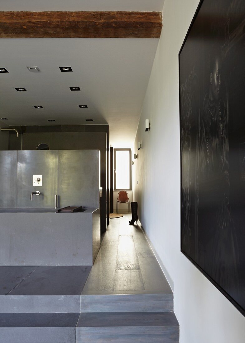 Open-plan designer bathroom - bathtub on platform and view into hallway with window