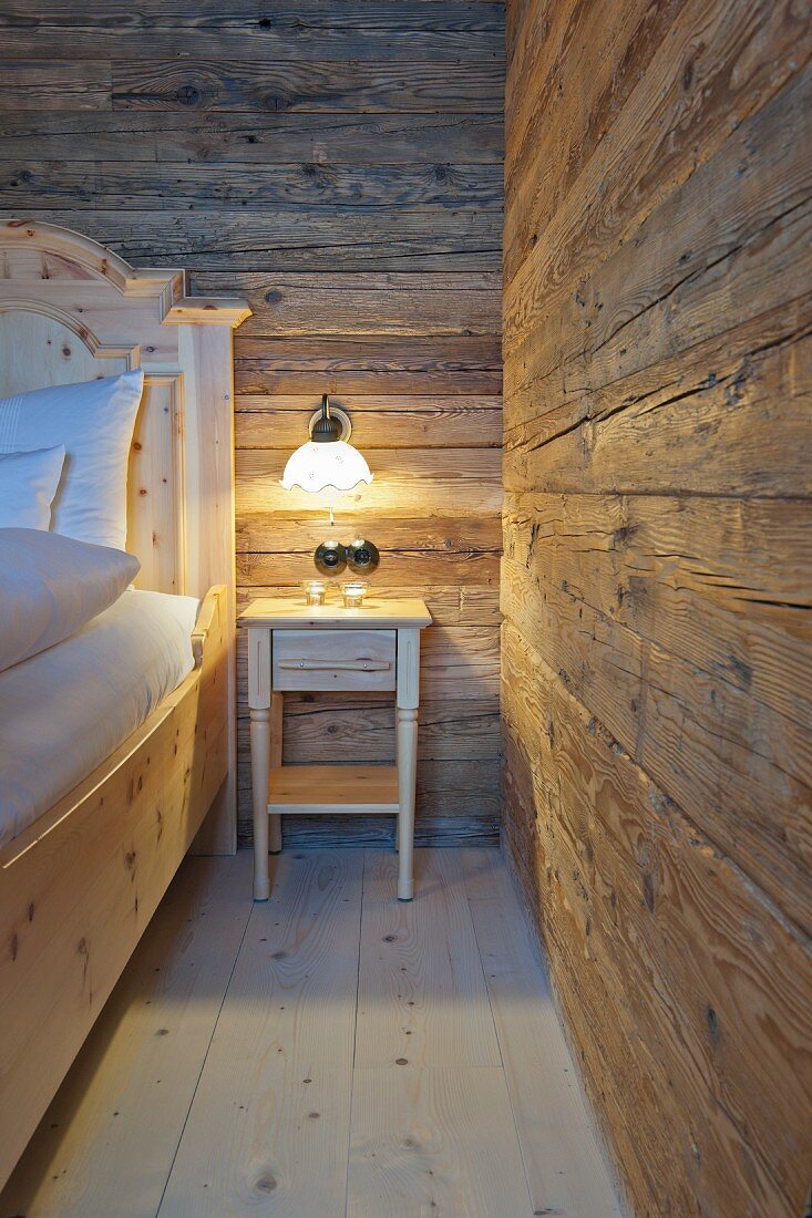 Nachtkästchen mit Beleuchtung im Schlafraum einer Holzhütte