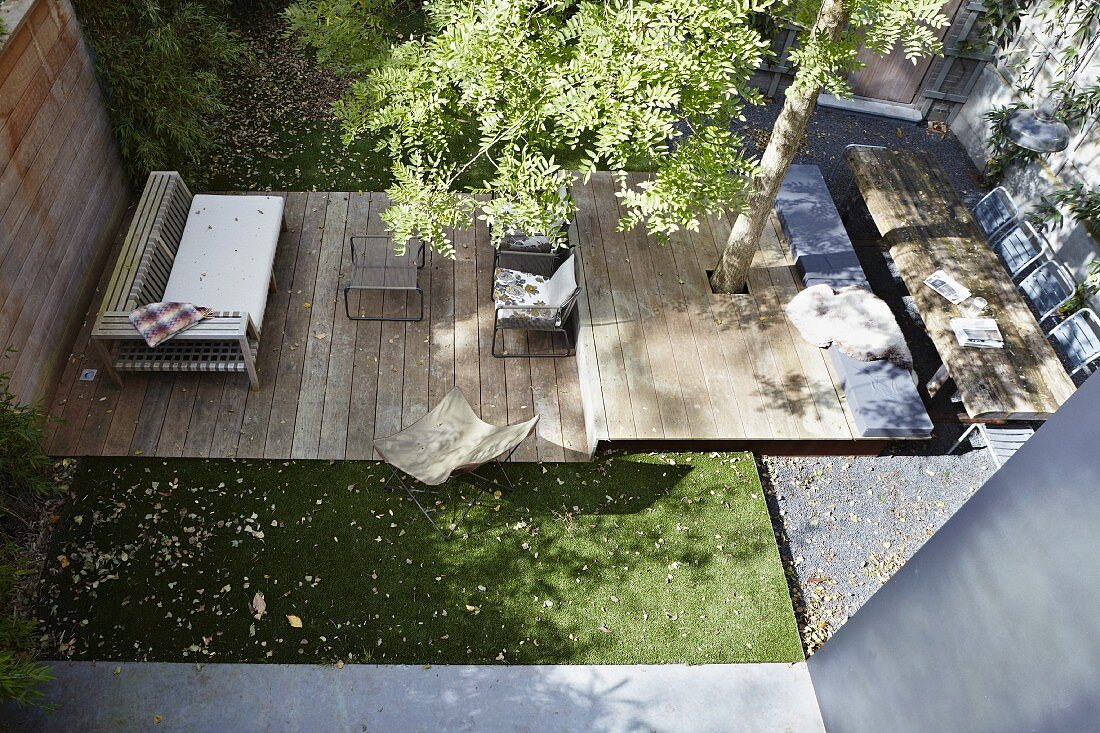 Läuferartig gestaltete Terrasse mit mehreren Ebenen und integrierter Baum in sonnenbeschienen Stadtgarten