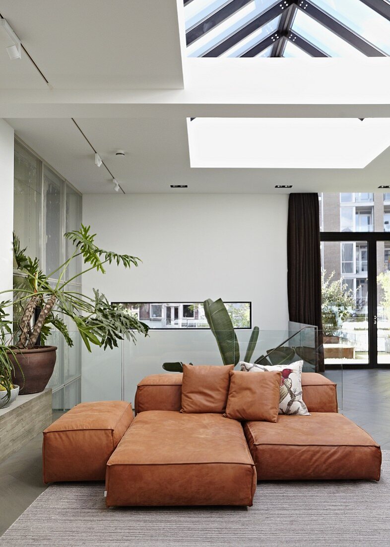 Verschieden grosse rostfarbene Bodenpolster in modernem Wohnraum unter Oberlicht im Deckenbereich