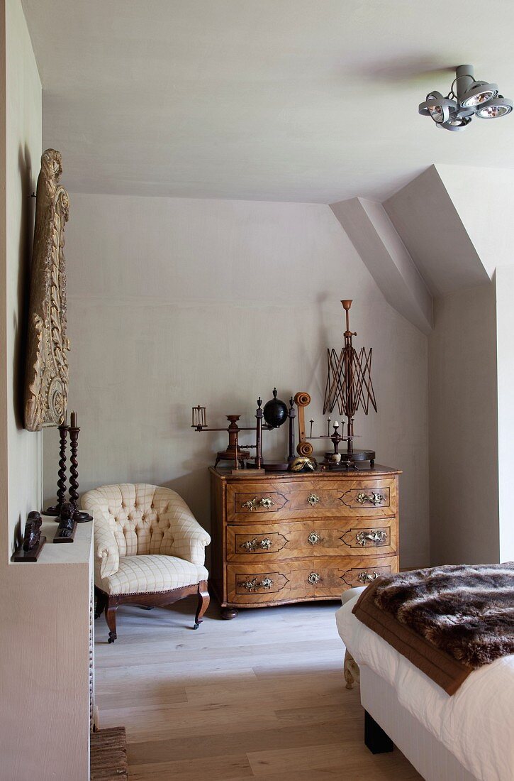 Altes Haushaltsgerät auf Barockkommode und antiker Sessel in Schlafzimmer unterm Dach