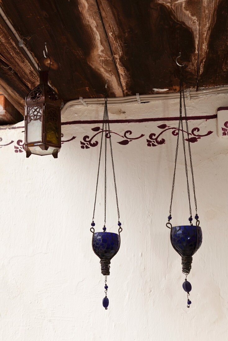 Blue glass tealight holders and lantern hanging from wooden ceiling beams