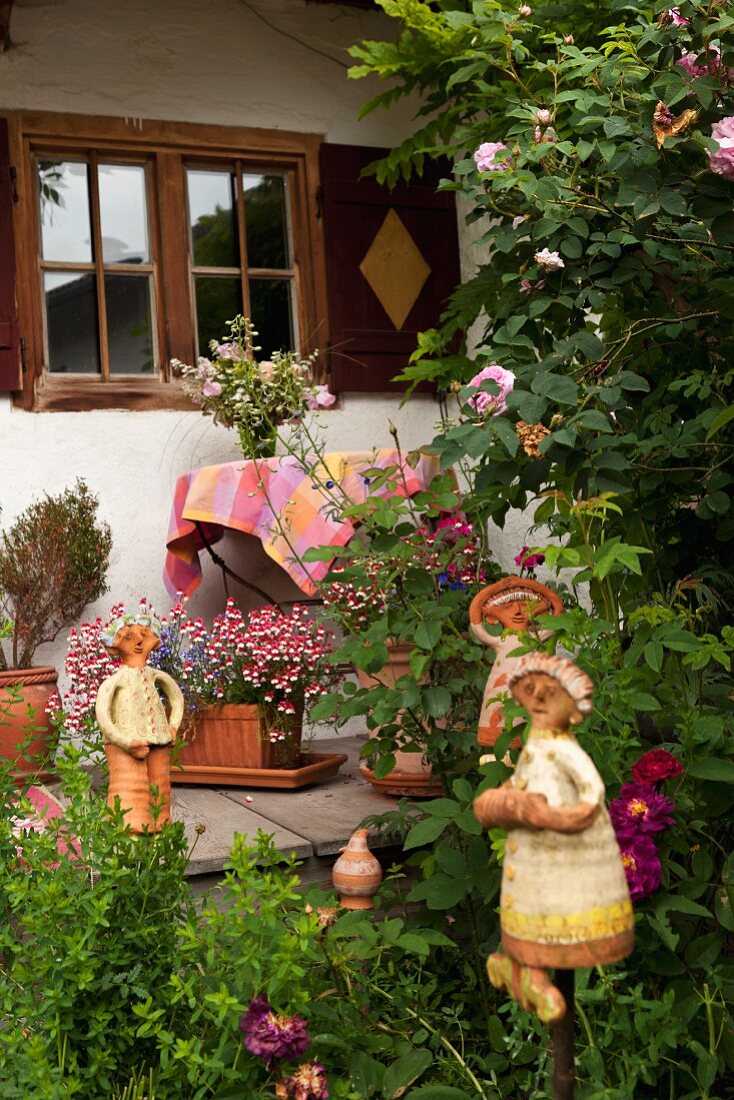Ceramic figurines in garden and on veranda of farmhouse