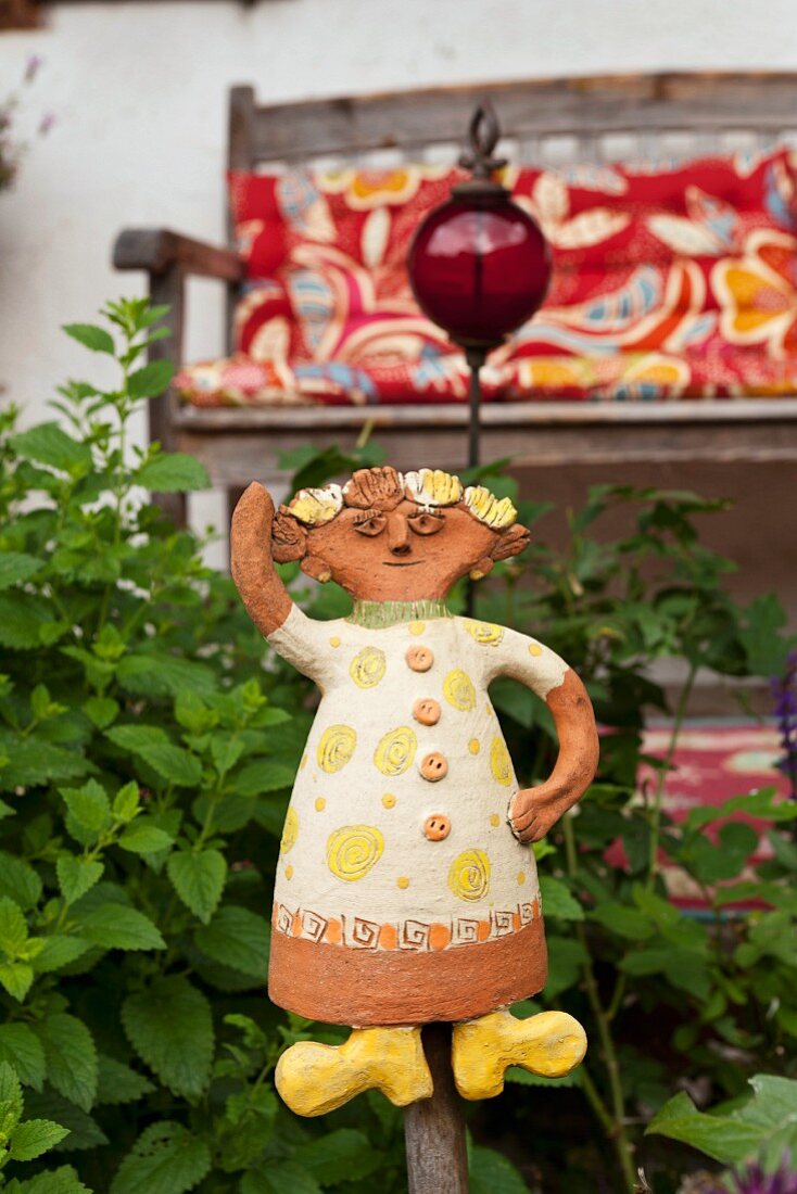 Keramikfigur im Garten, im Hintergrund Veranda mit Holzbank