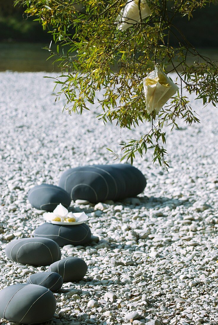 Sommerfest am Flussufer: als Deko grau bemalte Steine mit Streifenmuster auf dem Kiesbett