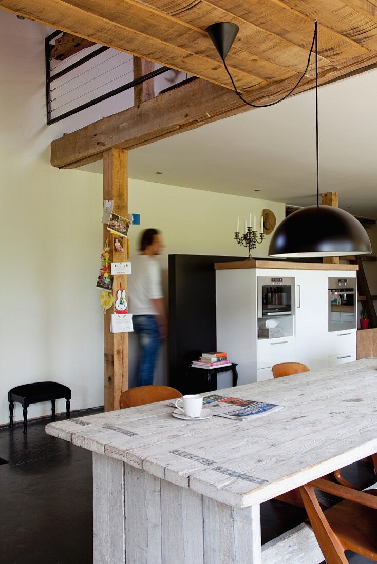 Rustic table in open-plan kitchen in modern interior