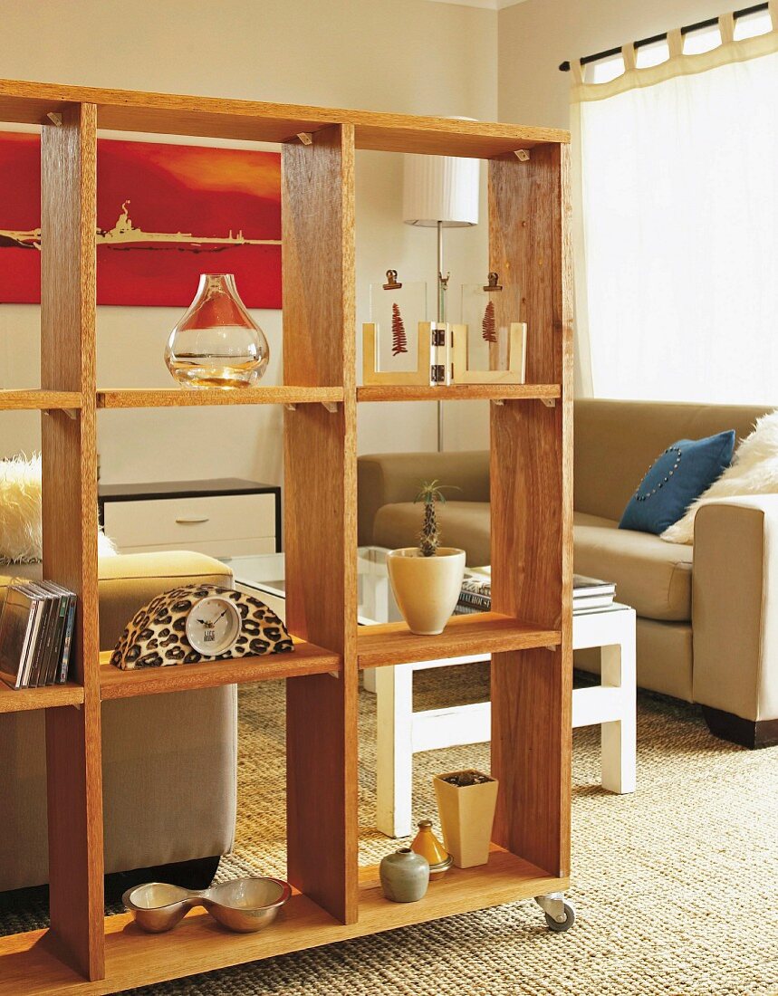 Movable shelving made of natural wood as partition in front of classic lounge area