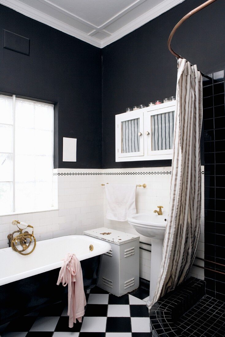 Black and white bathroom with Victorian bathtub and shower area