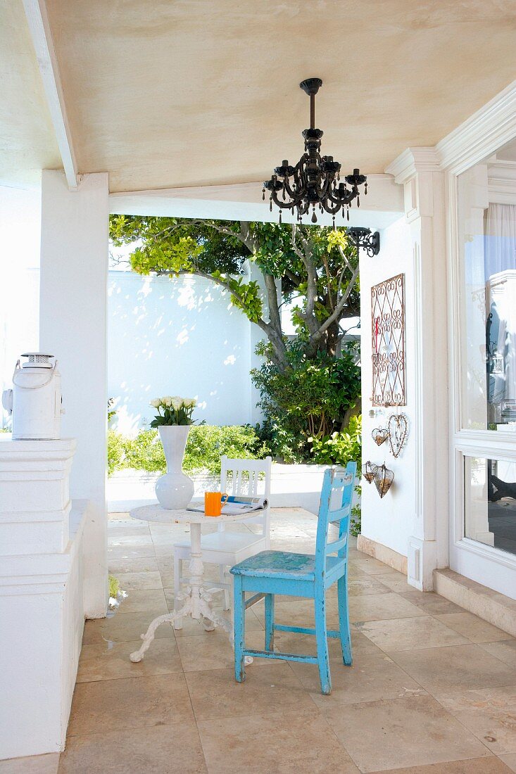 Blau lackierter Stuhl und Bistrotisch auf Veranda in klassizistischem Stil einer mediterranen Villa
